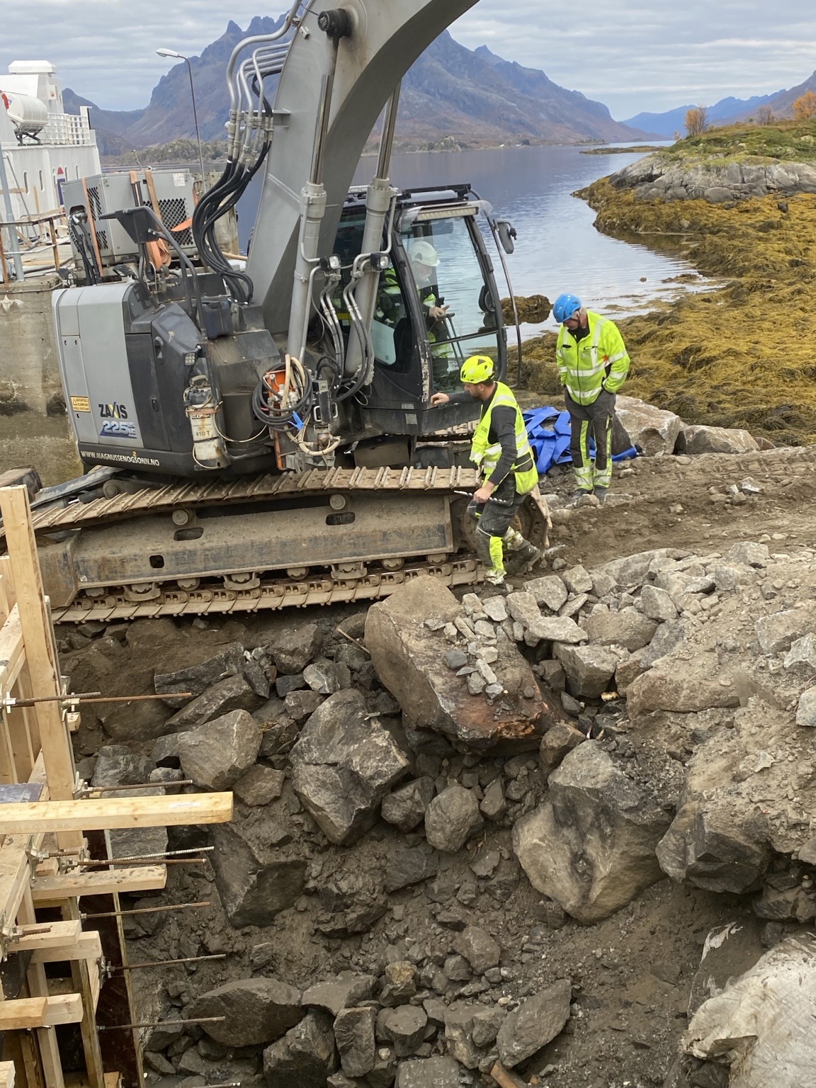 Gravemaskin og mannskap arbeider i steinmassene ved Digermulen