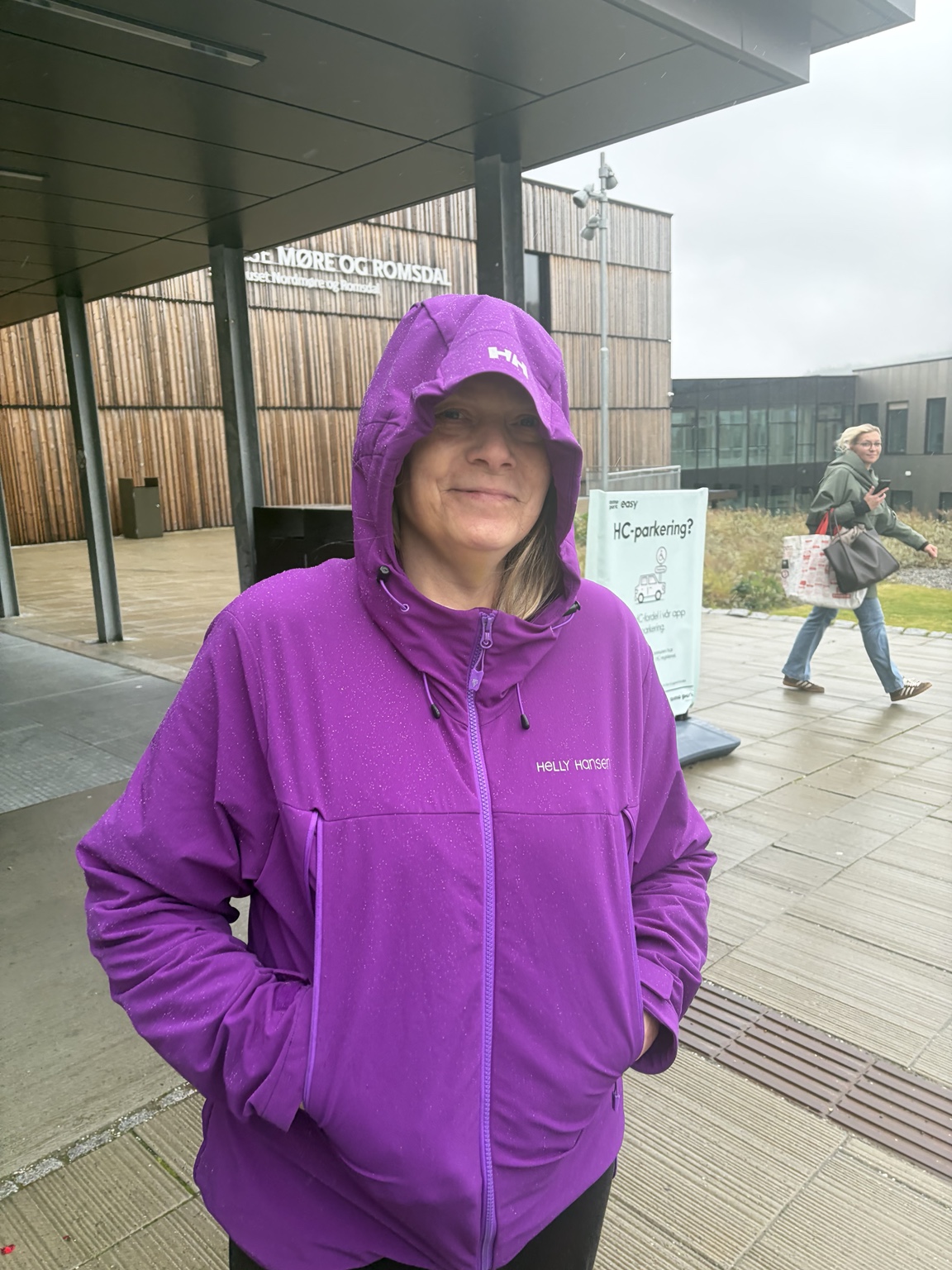 Rita Westvik utenfor sykehuset i lilla regnjakke